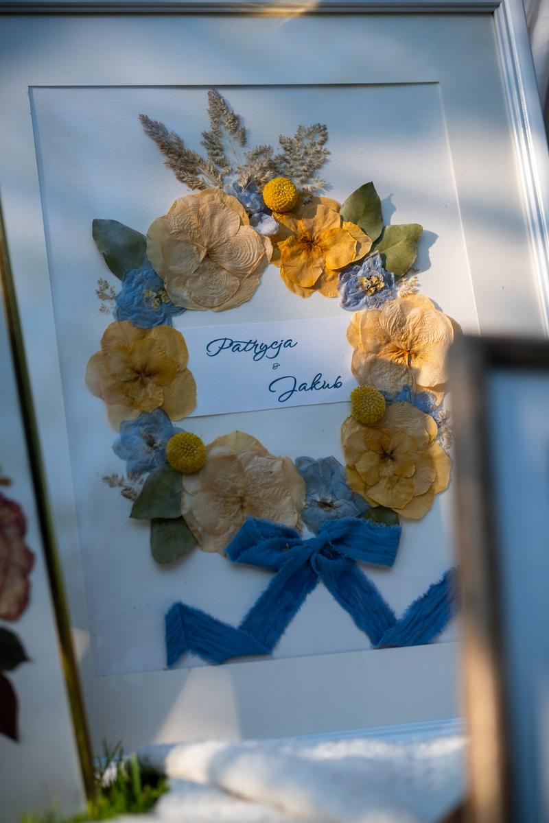 Elegancki obraz z suszonymi kwiatami w białej ramce, wieniec z bukietu ślubnego Patrycji i Jakuba, konserwacja kwiatów.