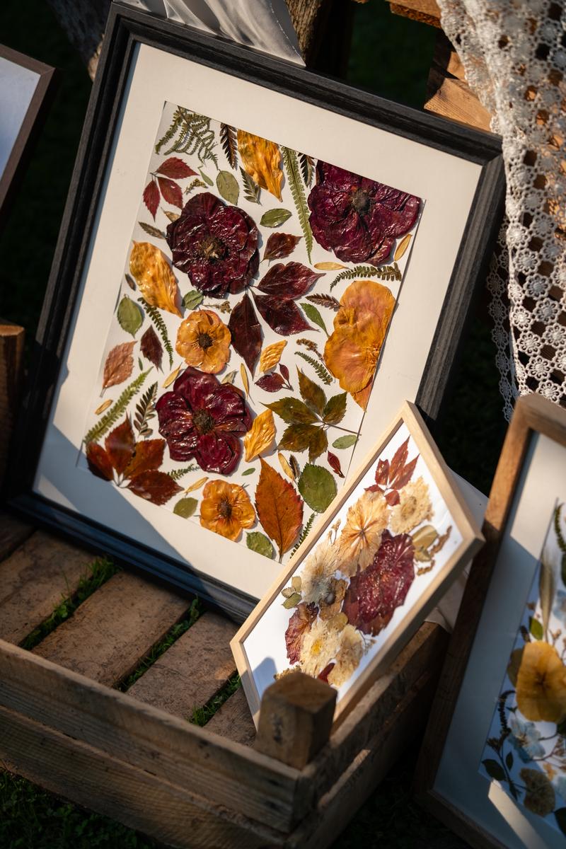 Dwa obrazy z suszonych kwiatów w ramkach na rustykalnej drewnianej powierzchni. Zdjęcie z wyższej perspektywy od Karokwiaty.