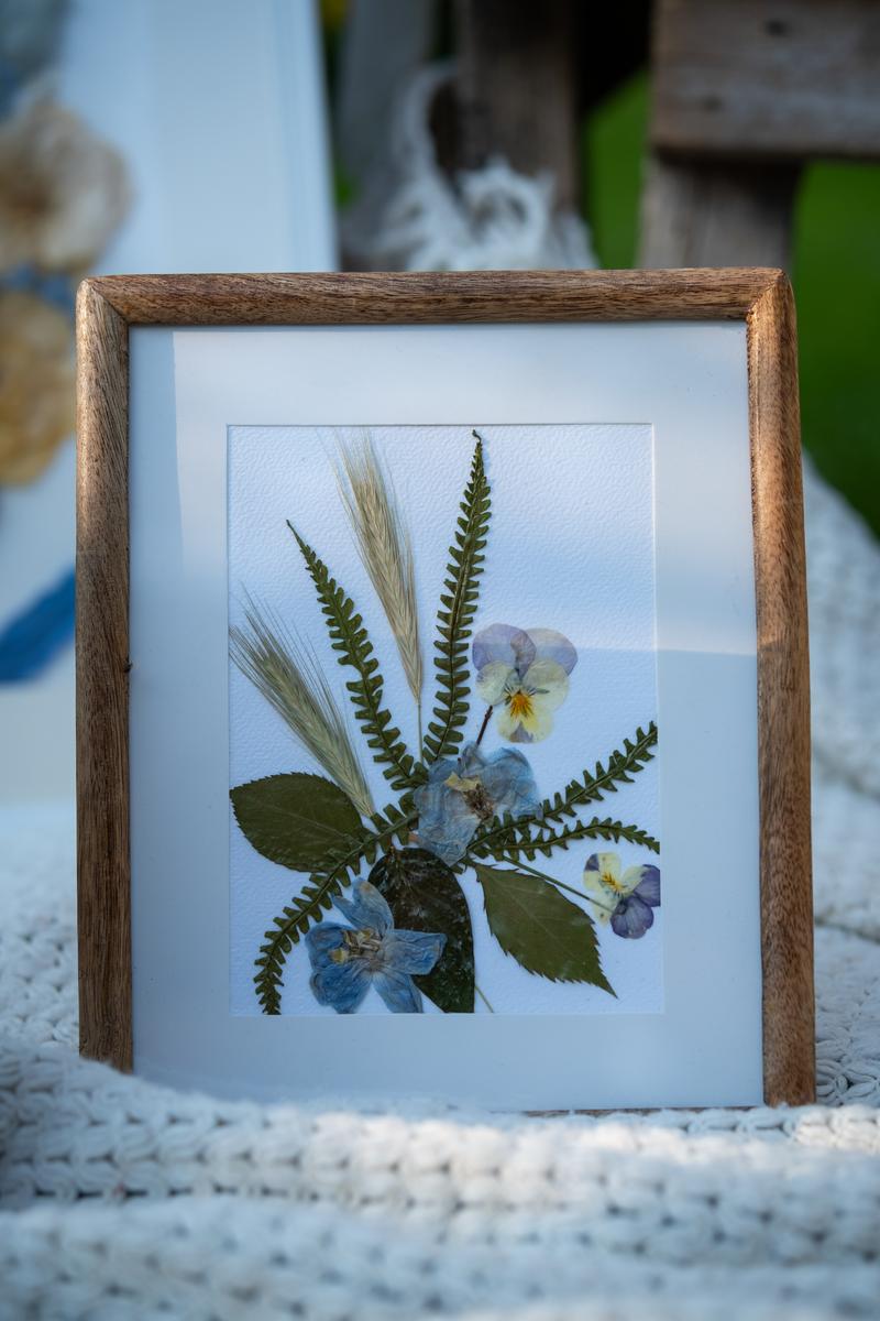 Subtelna kompozycja z suszonych kwiatów w drewnianej ramce. Niebieskie i fioletowe kwiaty z zielonymi liśćmi od Karokwiaty.