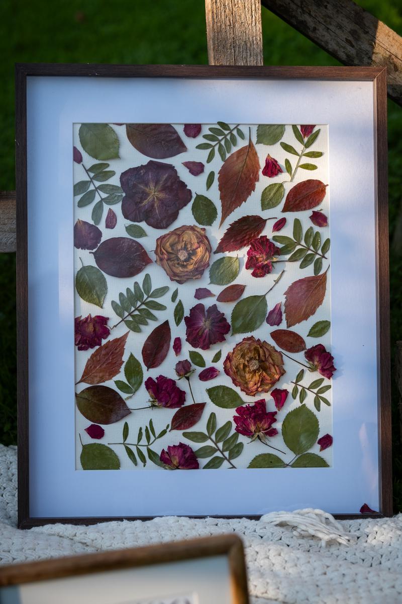 Elegancka kompozycja z suszonych kwiatów i liści w ciemnobrązowej ramce z białym passe-partout. Naturalny kolaż Karokwiaty.
