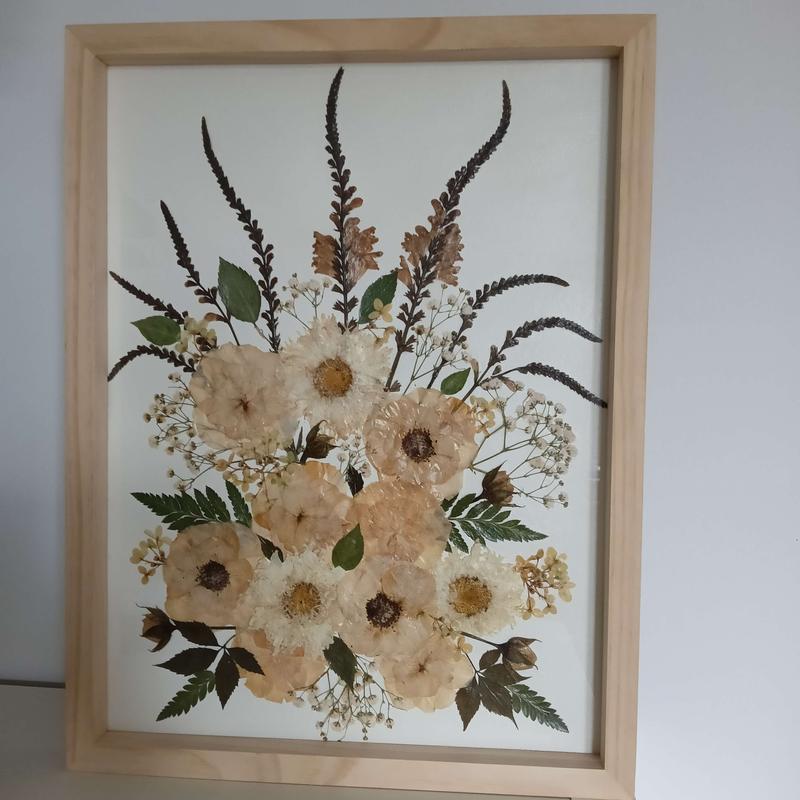 Elegancki obraz z suszonych kwiatów w jasnej drewnianej ramce, kompozycja w kształcie łzy w odcieniach kremu i brązu. Pamiątkowy obraz Karokwiaty.